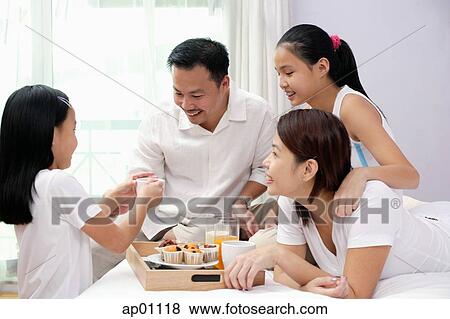 Family of four in bedroom, breakfast tray on the bed next to them View Large Photo Image Stock Photo - Family of four in bedroom, breakfast tray on the bed next to them. Fotosearch