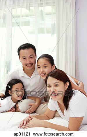 Stock Image - Family of four in smiling at camera. Fotosearch