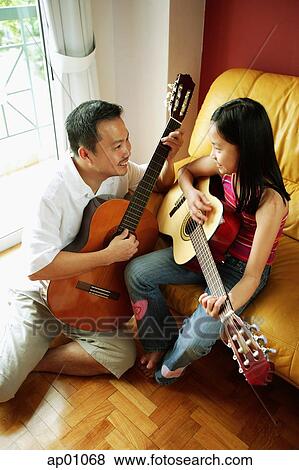 Father and daughter holding guitars, sitting face to face View Large Photo Image Stock Photo - Father and daughter holding guitars, sitting face to face. Fotosearch
