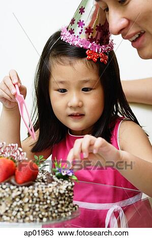 Stock Image - Father and daughter in front of birthday cake. Fotosearch