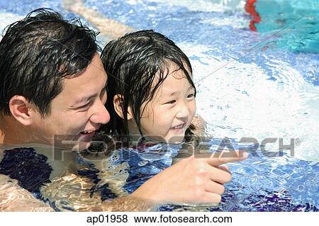 Father and daughter in swimming pool, father pointing with finger View Large Photo Image Stock Photo - Father and daughter in swimming pool, father pointing with finger. Fotosearch