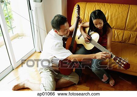 Father teaching daughter how to play the guitar View Large Photo Image Stock Photograph - Father teaching daughter how to play the guitar. Fotosearch