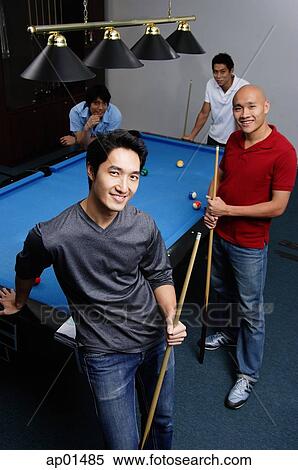 Four men standing around pool table, looking at camera View Large Photo Image Stock Photography - Four men standing around pool table, looking at camera. Fotosearch