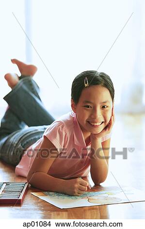 Girl lying on floor, with paper and crayons, looking at camera, hand on chin View Large Photo Image Picture - Girl lying on floor, with paper and crayons, looking at camera, hand on chin. Fotosearch