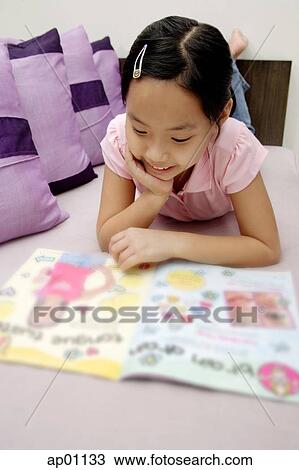 Girl reading magazine, lying on front View Large Photo Image Stock Image - Girl reading magazine, lying on front. Fotosearch