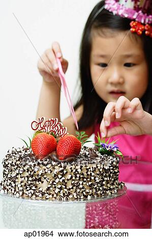Picture - Girl touching birthday cake. Fotosearch