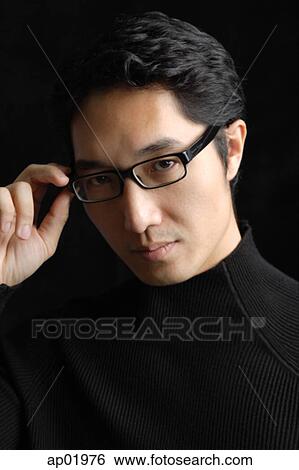 Stock Photograph - Man adjusting glasses, portrait. Fotosearch
