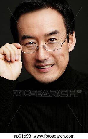 Man adjusting glasses, smiling, black background View Large Photo Image Stock Image - Man adjusting glasses, smiling, black background. Fotosearch