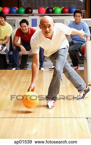 Man aiming bowling bowl, friends in the background, watching View Large Photo Image Stock Photo - Man aiming bowling bowl, friends in the background, watching. Fotosearch