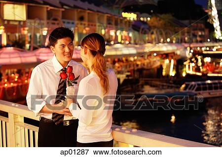 Man and woman standing face to face, woman holding roses View Large Photo Image Stock Photo - Man and woman standing face to face, woman holding roses. Fotosearch