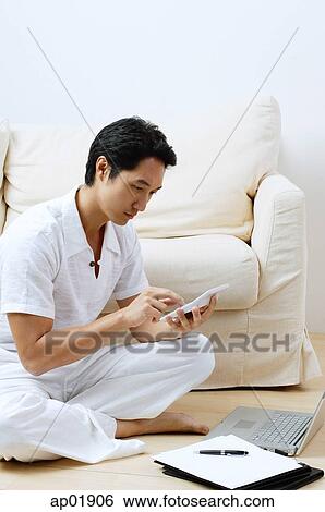 Stock Photograph - Man at home, using laptop and calculator. Fotosearch