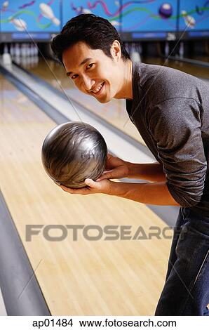 Man bending, holding bowling ball, smiling at camera View Large Photo Image Picture - Man bending, holding bowling ball, smiling at camera. Fotosearch