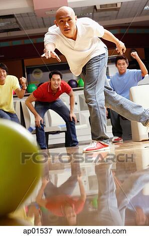 Stock Photo - Man bowling, friends in the background, cheering. Fotosearch