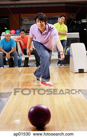 Man bowling, friends watching in the background View Large Photo Image Stock Image - Man bowling, friends watching in the background. Fotosearch