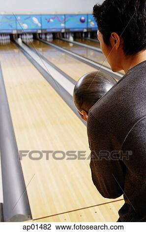 Stock Image - Man bowling, over the shoulder view. Fotosearch
