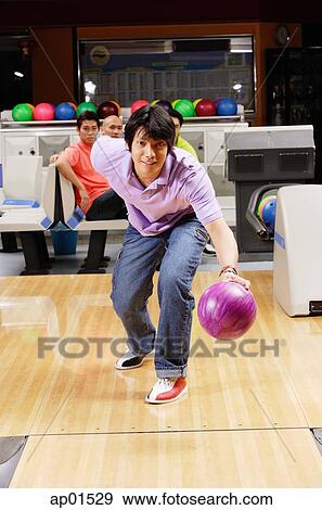 Stock Photo - Man bowling, people watching in the background. Fotosearch