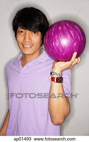 Stock Image - Man carrying bowling ball, smiling at camera. Fotosearch