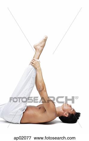Stock Photo - Man doing yoga, lying on back, holding leg. Fotosearch