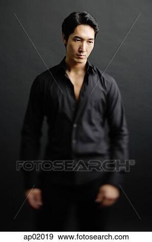 Man dressed in black, standing against black background View Large Photo Image Stock Photo - Man dressed in black, standing against black background. Fotosearch