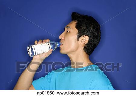 Stock Image - Man drinking water from disposable bottle. Fotosearch