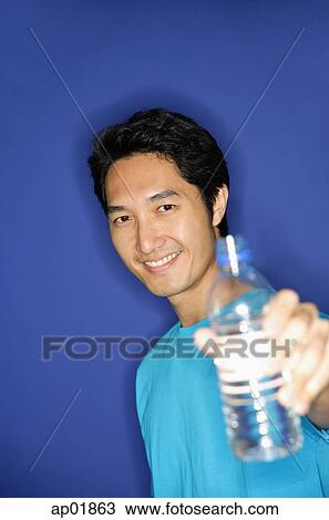 Man holding bottle of water towards camera View Large Photo Image Stock Image - Man holding bottle of water towards camera. Fotosearch