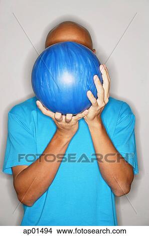 Picture - Man holding bowling ball in front of face. Fotosearch