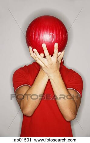 Stock Image - Man holding bowling ball in front of his face. Fotosearch