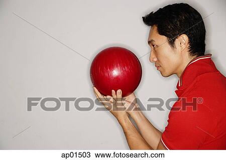 Man holding bowling ball in front of face, side view View Large Photo Image Stock Image - Man holding bowling ball in front of face, side view. Fotosearch