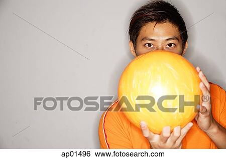 Stock Photograph - Man holding bowling ball in front of face. Fotosearch