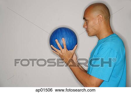 Man holding bowling ball in front of face, looking away View Large Photo Image Stock Photograph - Man holding bowling ball in front of face, looking away. Fotosearch