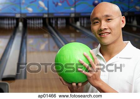 Stock Photograph - Man holding bowling ball, looking at camera. Fotosearch