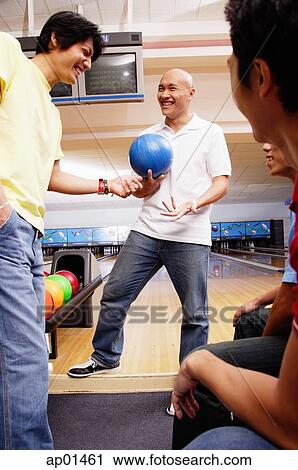 Man holding bowling ball, surrounded by other men View Large Photo Image Stock Image - Man holding bowling ball, surrounded by other men. Fotosearch