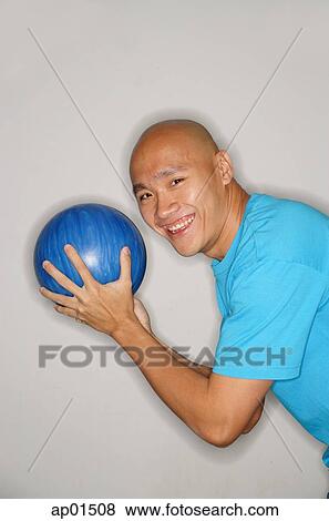 Stock Photo - Man holding bowling ball turning to smile at camera, side view. Fotosearch