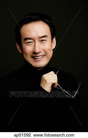 Man holding glasses, smiling, black background View Large Photo Image Stock Image - Man holding glasses, smiling, black background. Fotosearch