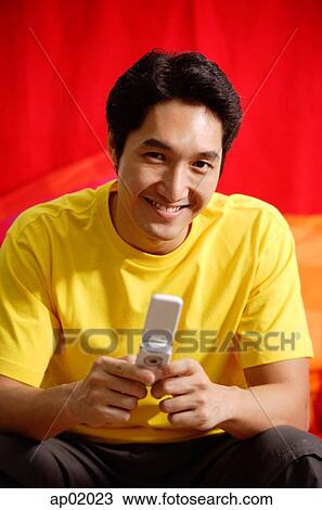 Man holding mobile phone, smiling at camera View Large Photo Image Stock Image - Man holding mobile phone, smiling at camera. Fotosearch
