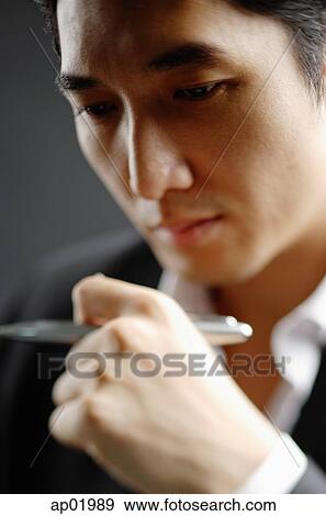 Man holding pen, looking away, head shot View Large Photo Image Stock Photo - Man holding pen, looking away, head shot. Fotosearch