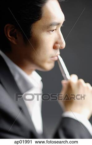 Man holding pen to mouth, side view View Large Photo Image Stock Image - Man holding pen to mouth, side view. Fotosearch