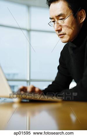 Stock Photography - Man in black turtleneck, using laptop. Fotosearch