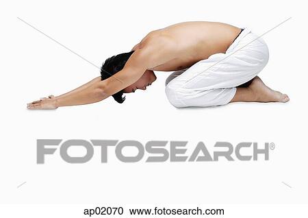 Stock Image - Man kneeling on floor, doing yoga. Fotosearch