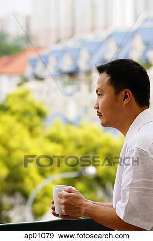 Man leaning on railing, looking away, holding mug View Large Photo Image Stock Photo - Man leaning on railing, looking away, holding mug. Fotosearch