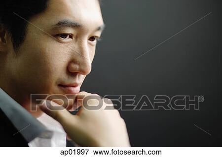 Stock Photo - Man looking away, hand on chin, head shot. Fotosearch