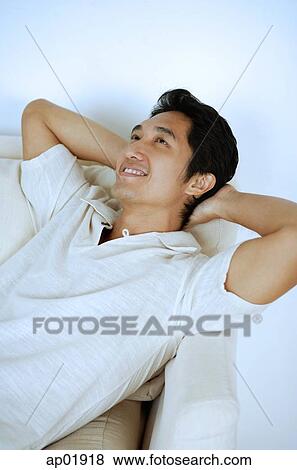 Man lying on sofa, hands behind head, smiling View Large Photo Image Stock Photo - Man lying on sofa, hands behind head, smiling. Fotosearch