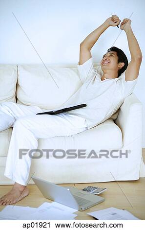 Man lying on sofa, sleeping, arms raised, laptop and documents on floor next to him View Large Photo Image Stock Image - Man lying on sofa, sleeping, arms raised, laptop and documents on floor next to him. Fotosearch