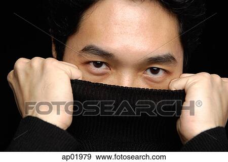 Stock Photo - Man pulling turtleneck over face, looking at camera. Fotosearch