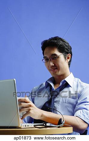 Stock Image - Man sitting in front of laptop, holding mug. Fotosearch