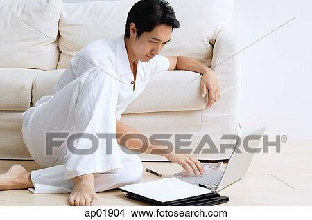 Man sitting on floor, using laptop View Large Photo Image Picture - Man sitting on floor, using laptop. Fotosearch
