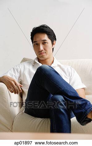 Man sitting on sofa, looking at camera View Large Photo Image Stock Photo - Man sitting on sofa, looking at camera. Fotosearch