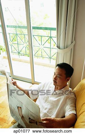 Man sitting on sofa reading newspaper View Large Photo Image Stock Photo - Man sitting on sofa reading newspaper. Fotosearch