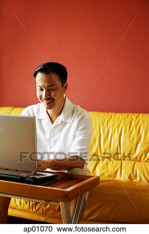Man sitting on sofa, using laptop View Large Photo Image Stock Image - Man sitting on sofa, using laptop. Fotosearch