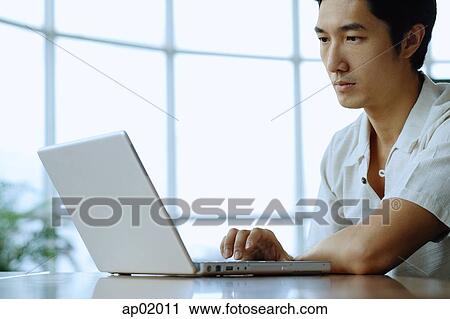 Stock Image - Man sitting, using laptop. Fotosearch